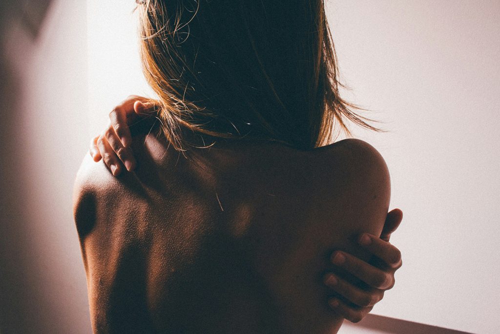 woman holding her arms around her back